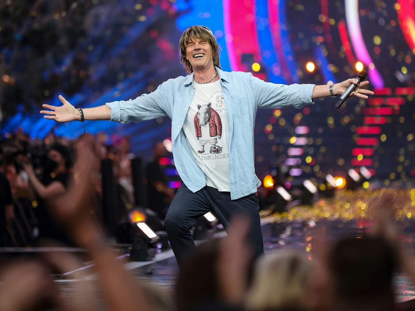 Ballermann-Star Mickie Krause mit Mikrofon auf einer Bühne. Vor ihm jubelnd sein Publikum.