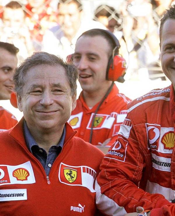 Michael Schumacher und Jean Todt lächeln gemeinsam im Fahrerlager der Formel 1.
