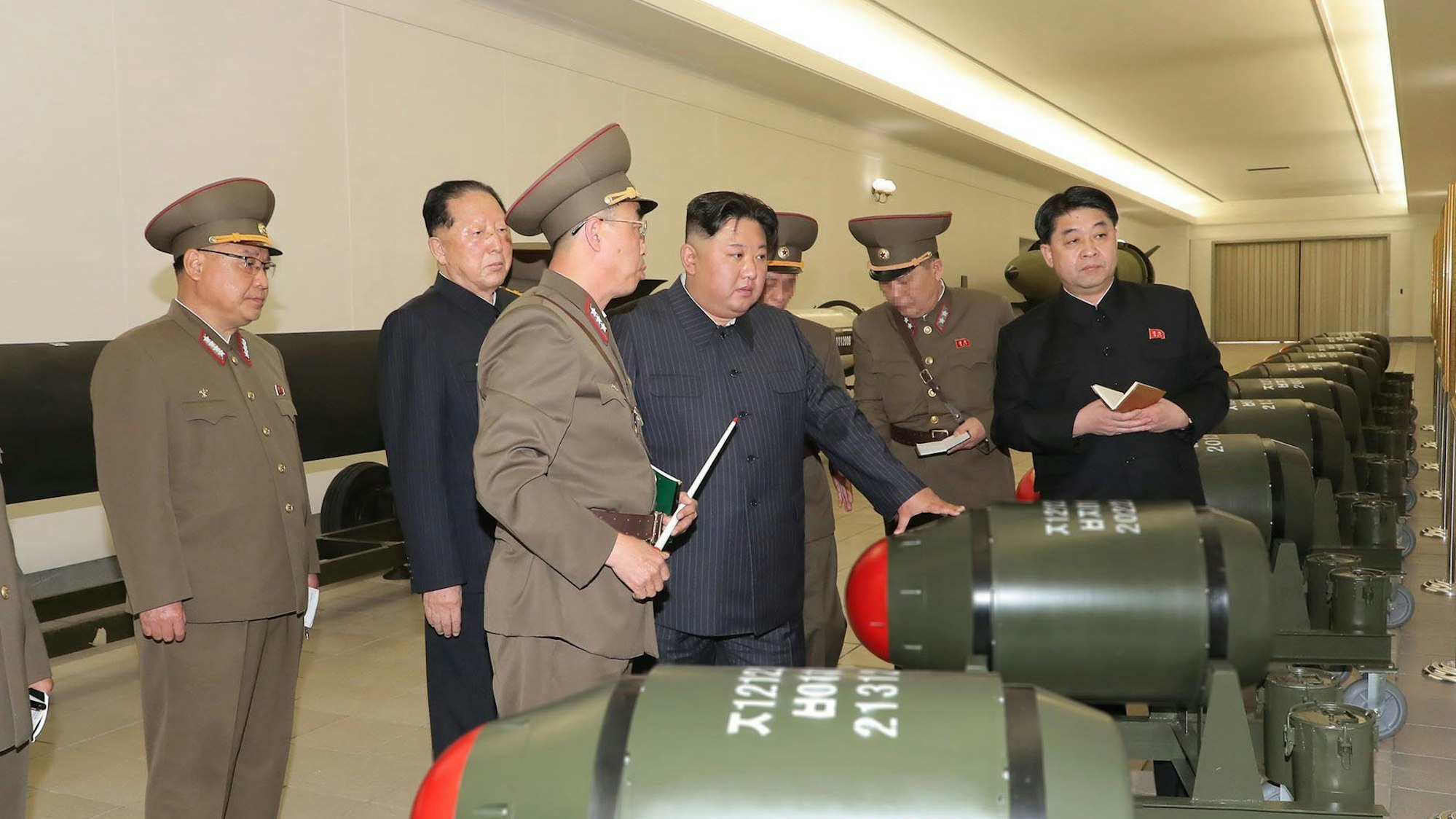 Hier zu sehen, Machthaber Kim Jong-un im Nuklearwaffeninstitut in Nordkorea. Um ihn herum stehen weitere Personen in militärischen Uniformen.
