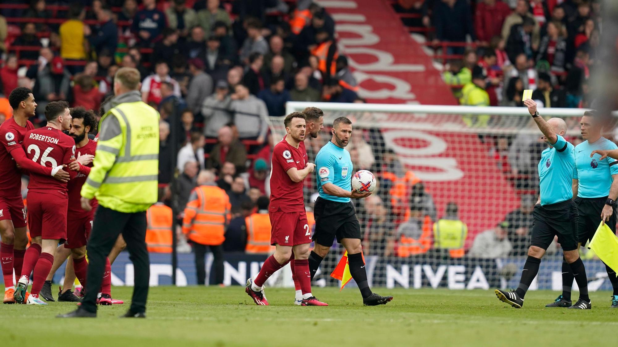 Referee Paul Tierney (r.) zeigt Andrew Robertson (l.) vom FC Liverpool die Gelbe Karte. Zuvor hatte Linienrichter Constantine Hatzidakis (M.) ihn per Ellbogenstoß attackiert.