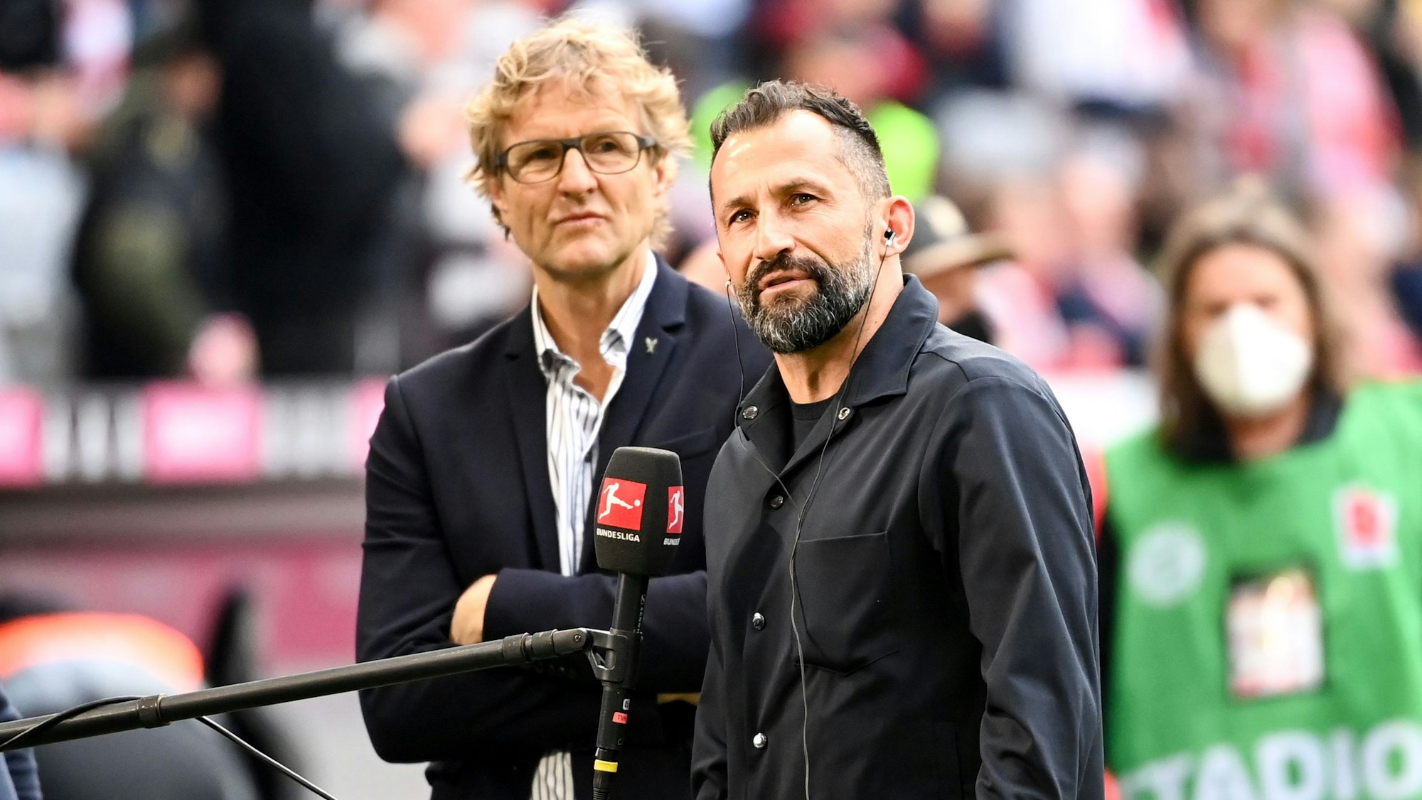 Münchens Sportvorstand Hasan Salihamidzic und Pressesprecher Dieter Nickles stehen bei einem TV-Interview vor dem Spiel.