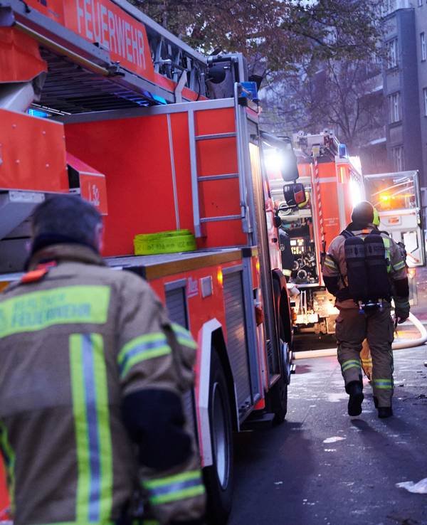 Zwei Feuerwehrmänner laufen zu den Einsatzfahrzeugen.