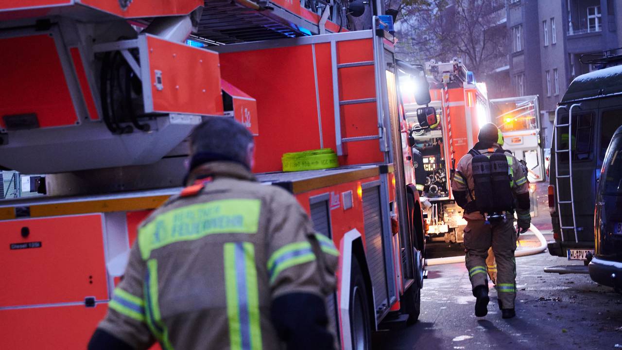 Zwei Feuerwehrmänner laufen zu den Einsatzfahrzeugen.
