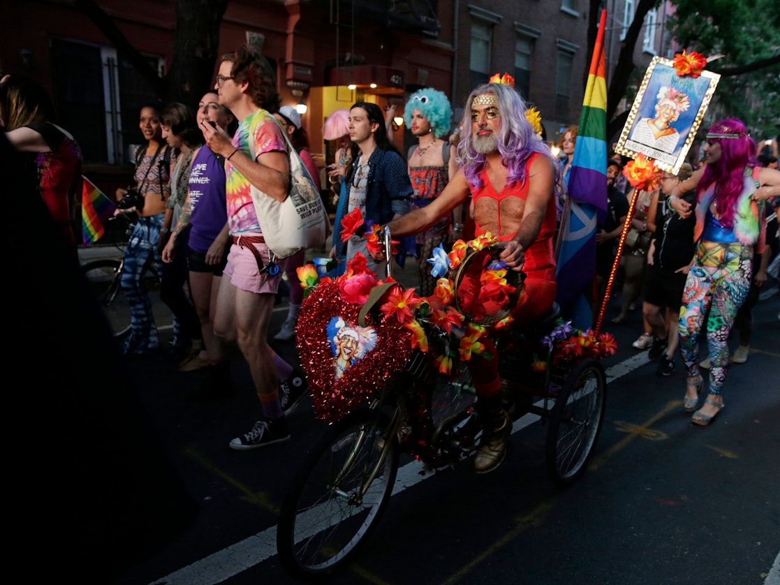 Menschen ziehen mit Regenbogenfahnen durch die Straßen.