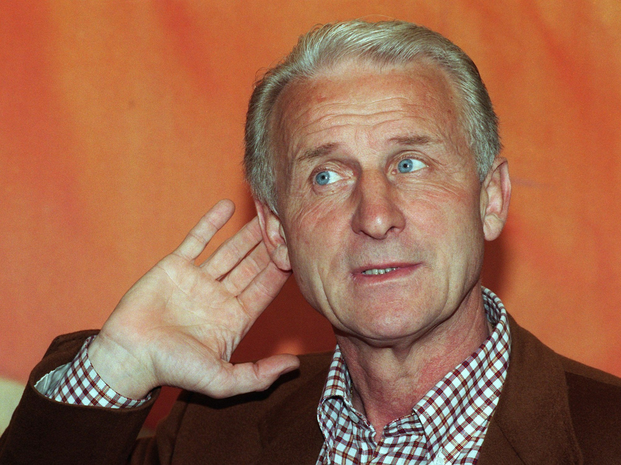 Giovanni Trapattoni, damals Trainer des FC Bayern München, hört bei einer Pressekonferenz seines Vereins sehr aufmerksam zu und hält dafür seine Hand an sein rechtes Ohr.