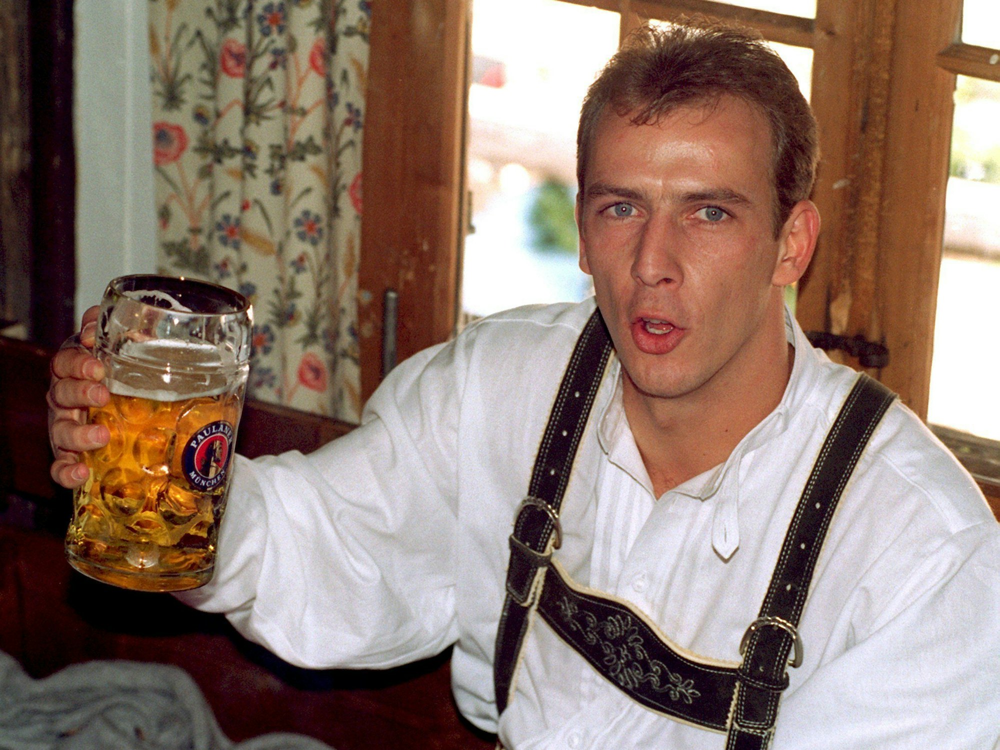 Mario Basler trägt eine bayerische Tracht und hält einen Maßkrug in der Hand.