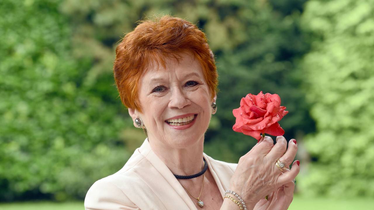 Die Schauspielerin Lotti Krekel posiert mit einer Rose in den Händen.