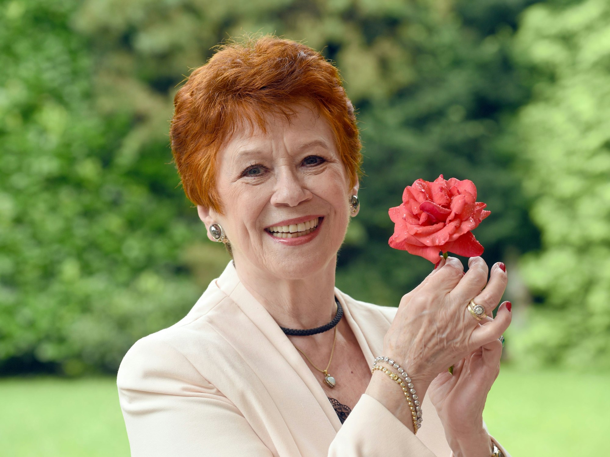 Die Schauspielerin Lotti Krekel posiert mit einer Rose in den Händen.