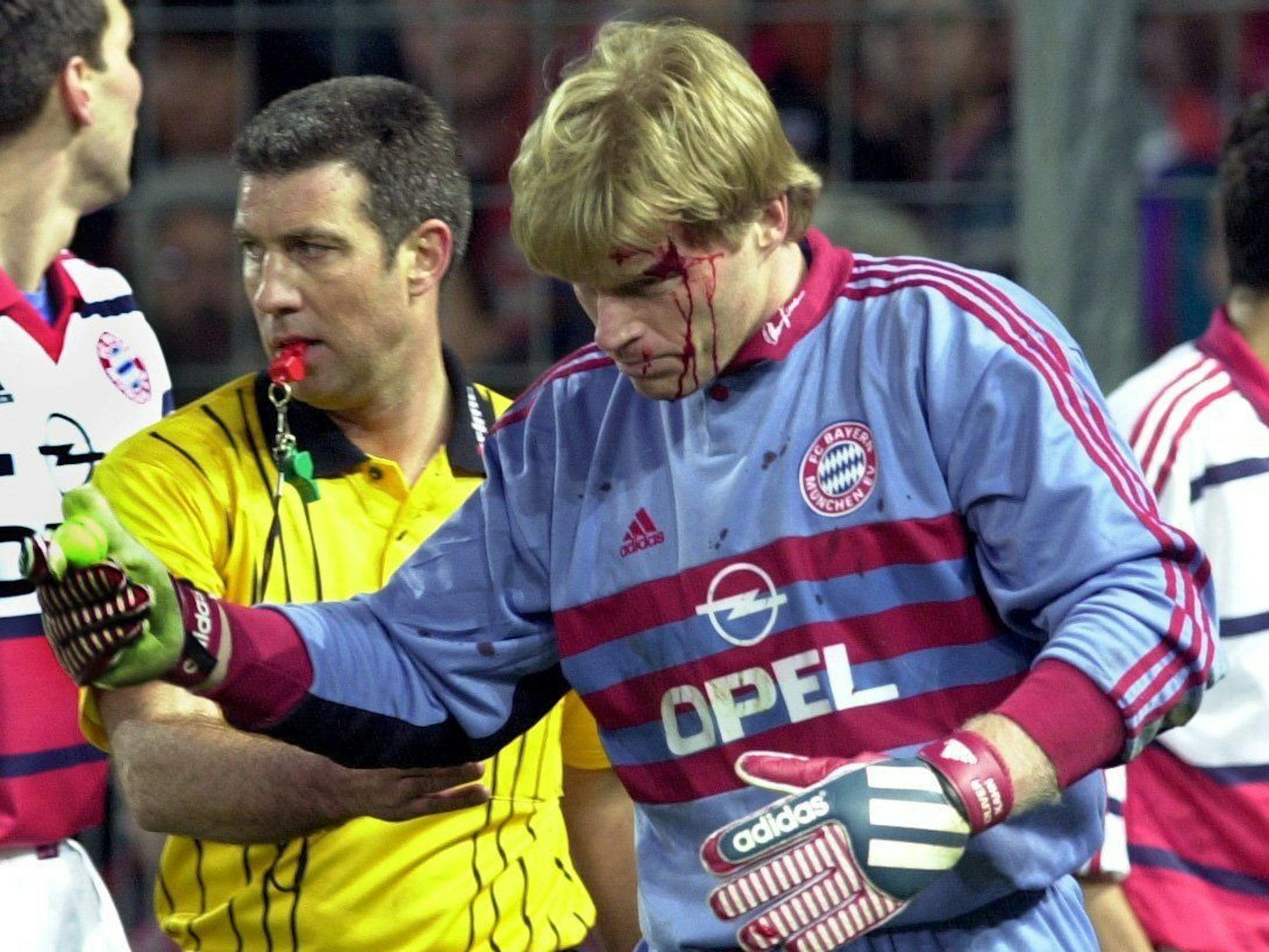 Schiedsrichter Uwe Kemmling und der aus dem Publikum auf den Bayern-Torhüter Oliver Kahn geworfene Golfball in der Hand des mit Blut überströmten Kahn am 12.04.2000 in Freiburg.