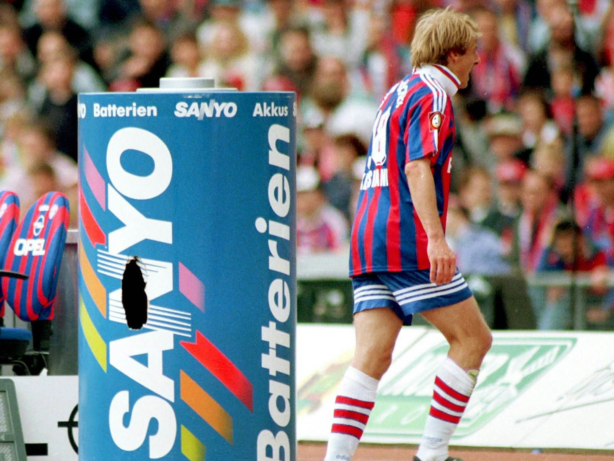 Jürgen Klinsmann vom FC Bayern München ist nach seiner Auswechslung wütend und verlässt das Feld in Richtung Kabine. Auf dem Weg hat er gegen eine Werbetonne getreten, in der sich nun ein Loch befindet.