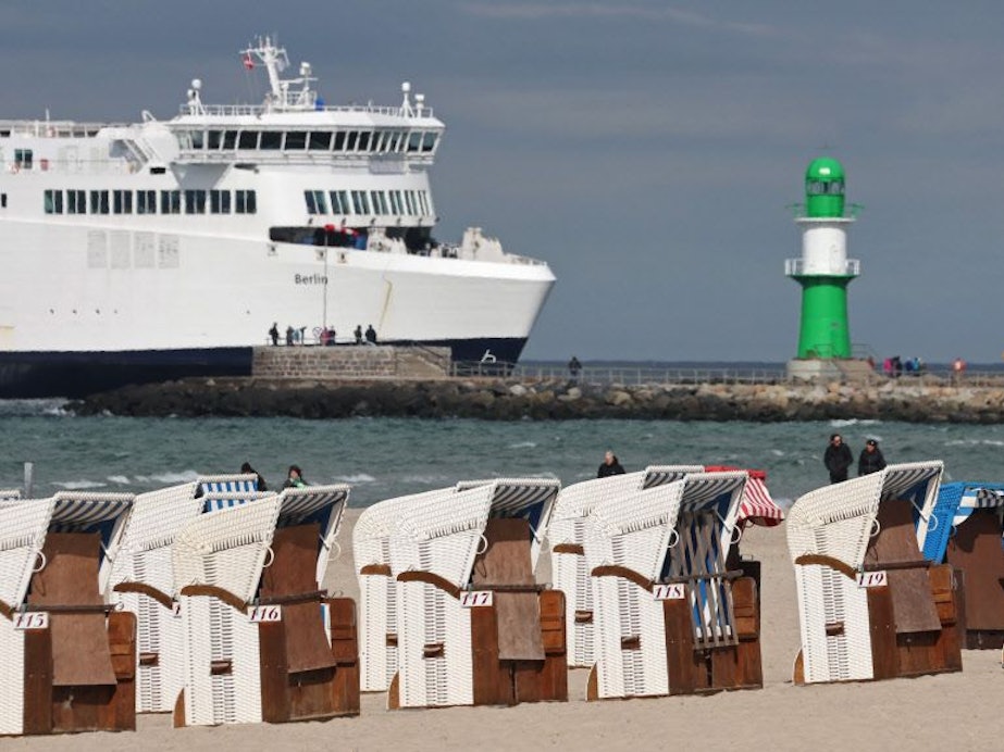 Zu sehen sind mehrere Strandkörbe sowie ein Kreuzfahrtschiff an der Ostsee.