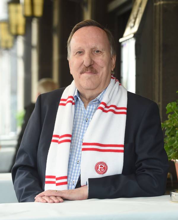 Dieter Bierbaum steht am Tisch und lächelt in die Kamera.