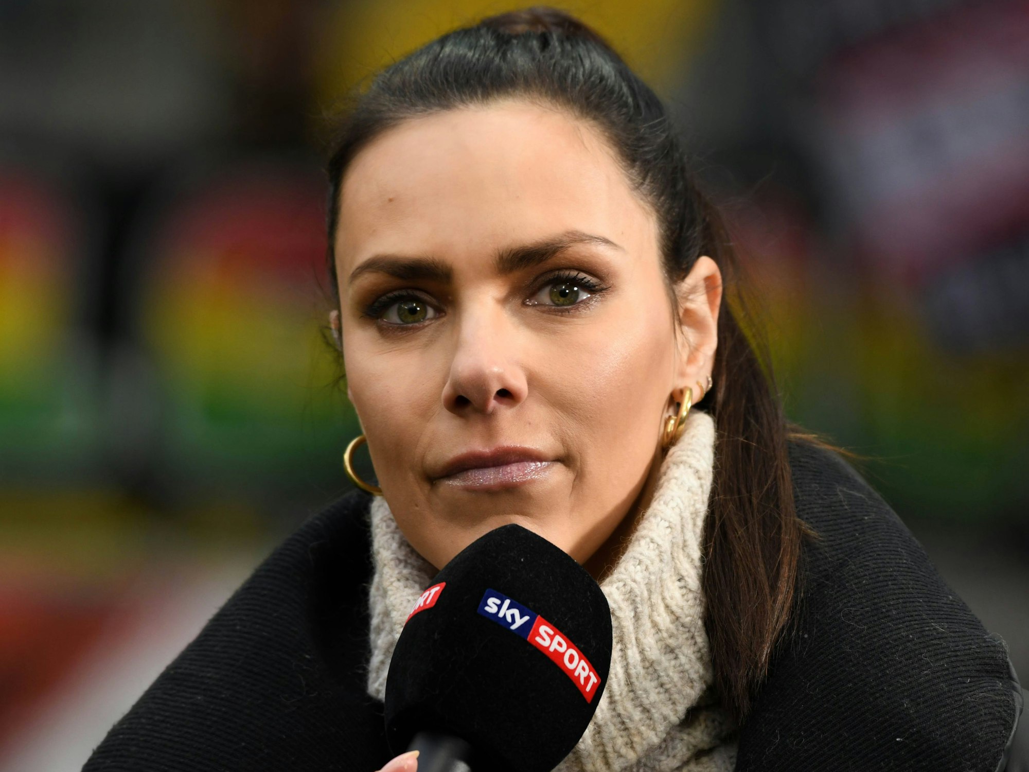 Esther Sedlaczek steht mit einem Sky-Mikro im Stadion.