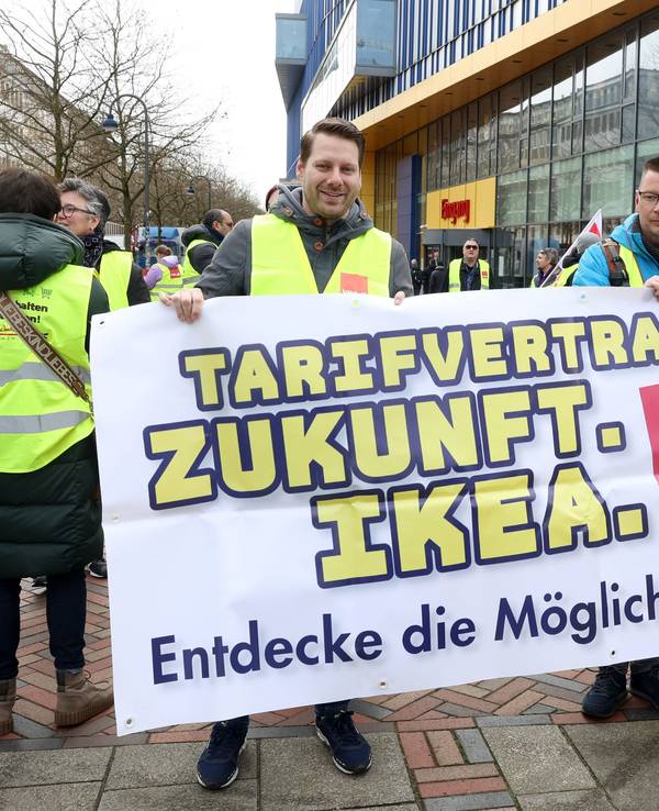 Streikende Ikea-Mitarbeiter stehen bei einer Kundgebung vor einer Ikea-Filiale in Hamburg-Altona und halten ein Transparent mit der Aufschrift „Tarifvertrag. Zukunft. Ikea. Endecke die Möglichkeiten!“