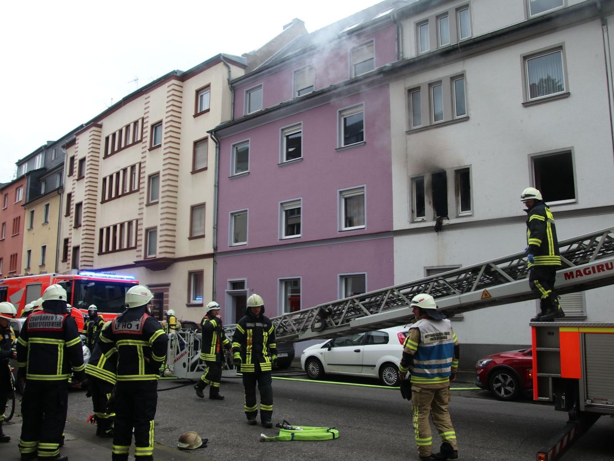 Feuerwehrleute stehen vor einem brennenden Gebäude.