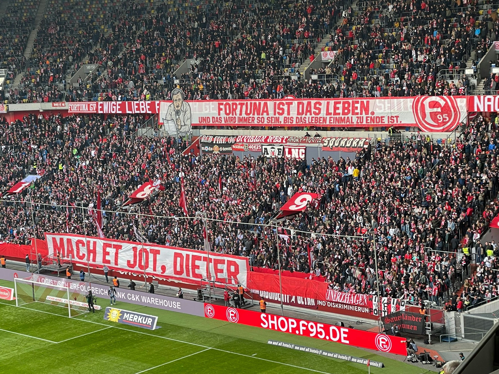 Fans von Fortuna Düsseldorf hissen ein Banner in Gedenken an den verstorbenen Stadionsprecher Dieter Bierbaum.