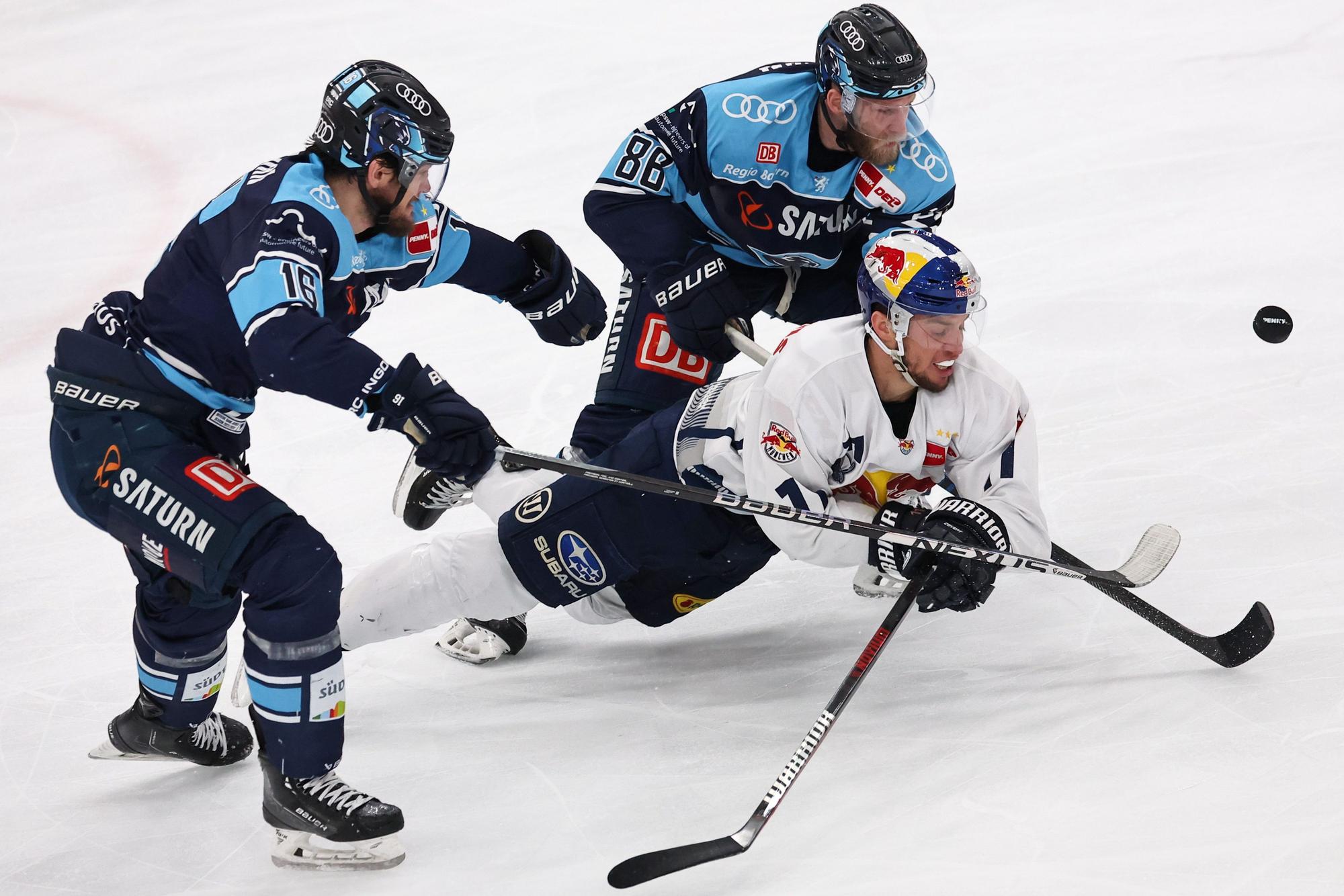 Daniel Pietta und Tye McGinn vom ERC Ingolstadt kämpfen mit Frederik Tiffels vom EHC München um den Puck.