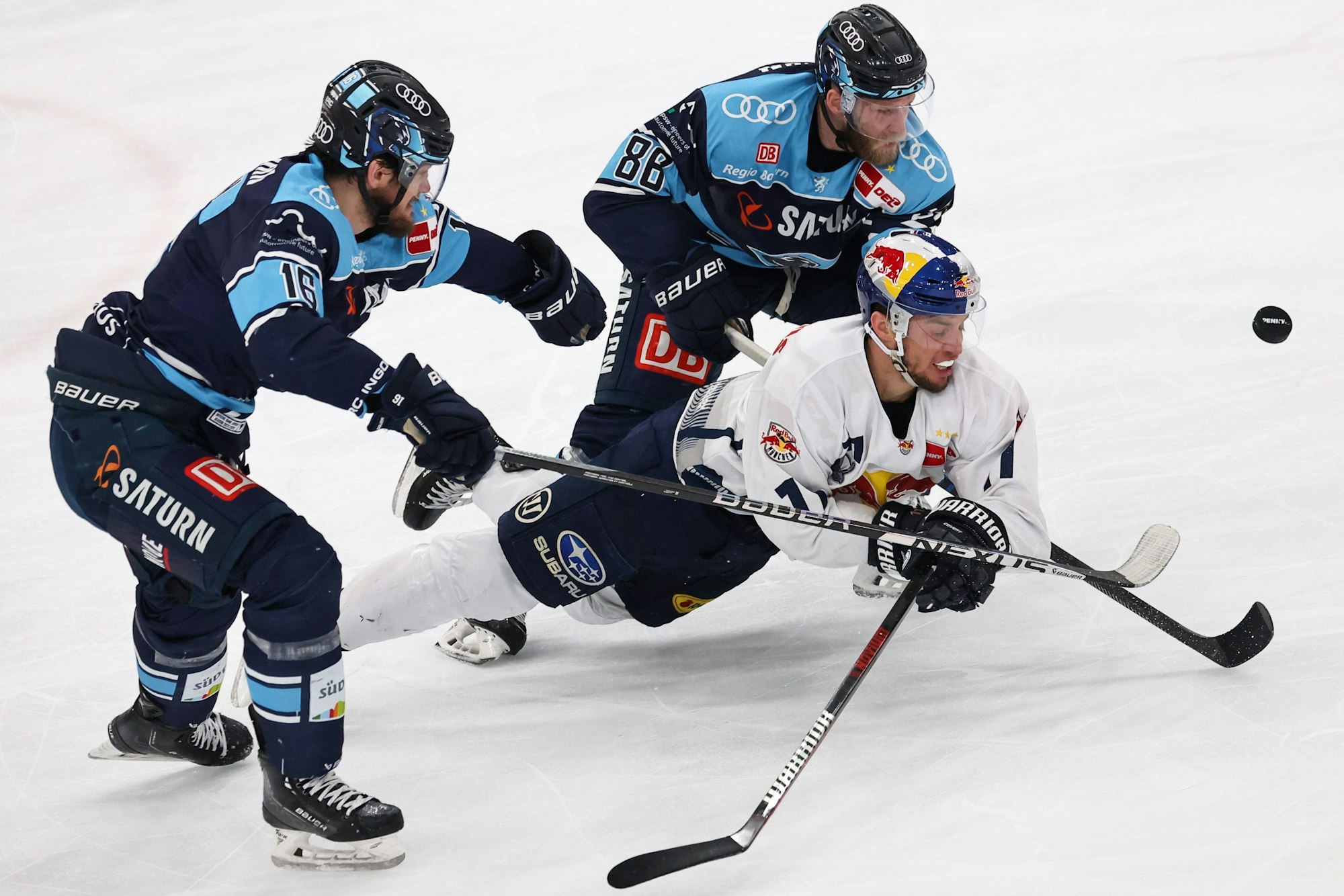 Daniel Pietta und Tye McGinn vom ERC Ingolstadt kämpfen mit Frederik Tiffels vom EHC München um den Puck.