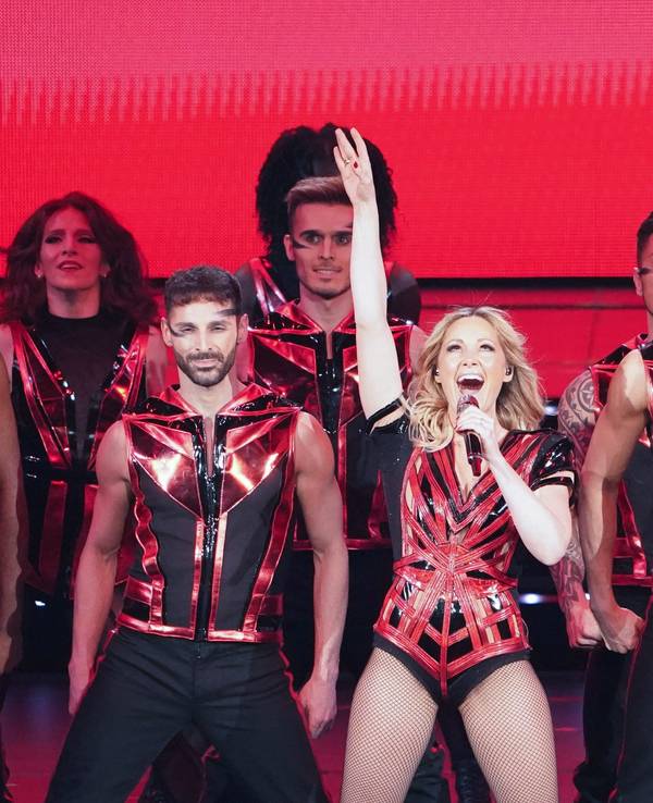 Hier zu sehen, Helene Fischer in einem schwarz-roten Kostüm zusammen mit ihren Tänzerinnen und Tänzern auf der Bühne in Hamburg.