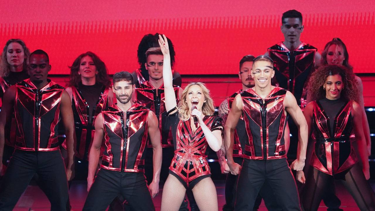 Hier zu sehen, Helene Fischer in einem schwarz-roten Kostüm zusammen mit ihren Tänzerinnen und Tänzern auf der Bühne in Hamburg.