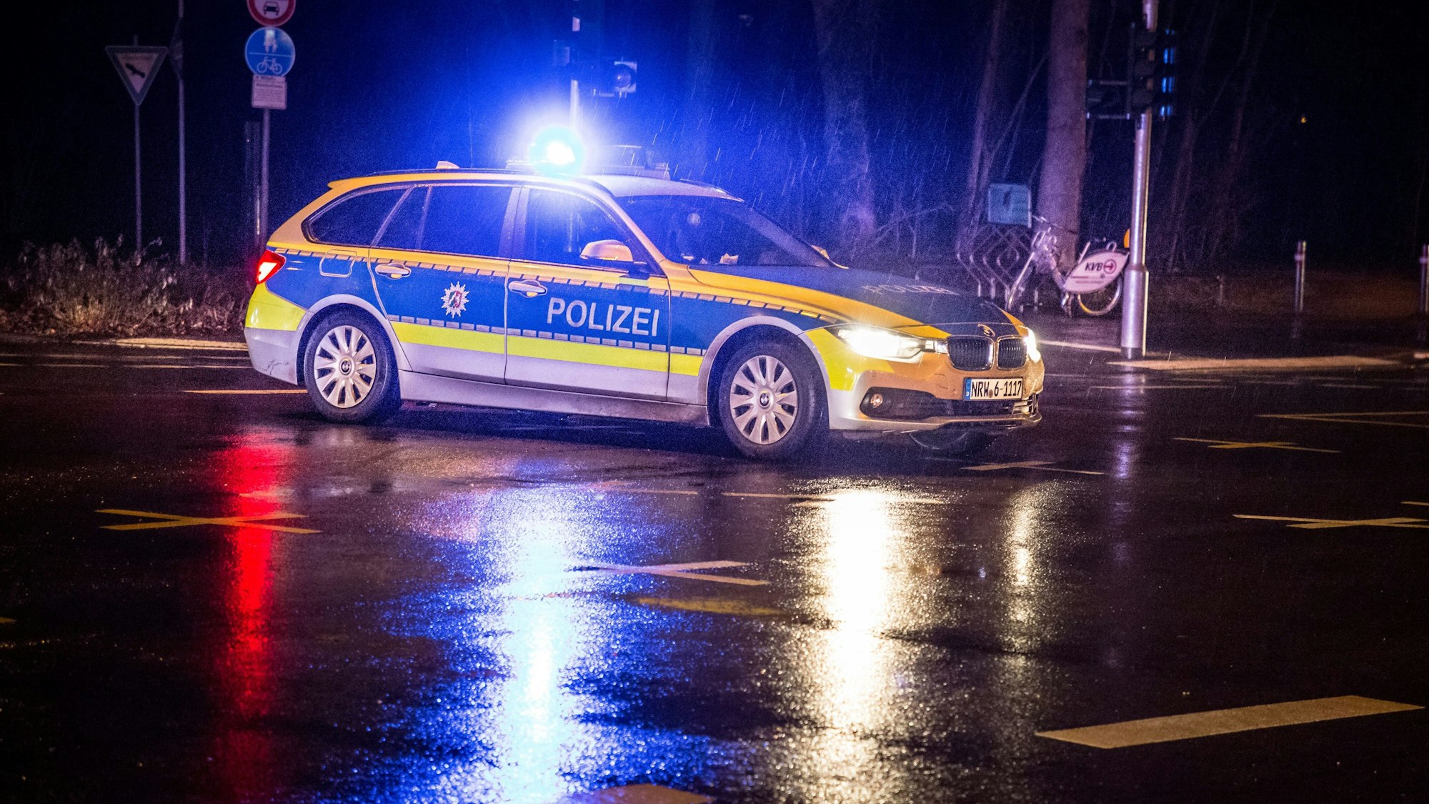 Ein Polizeiauto steht nachts im Regen.