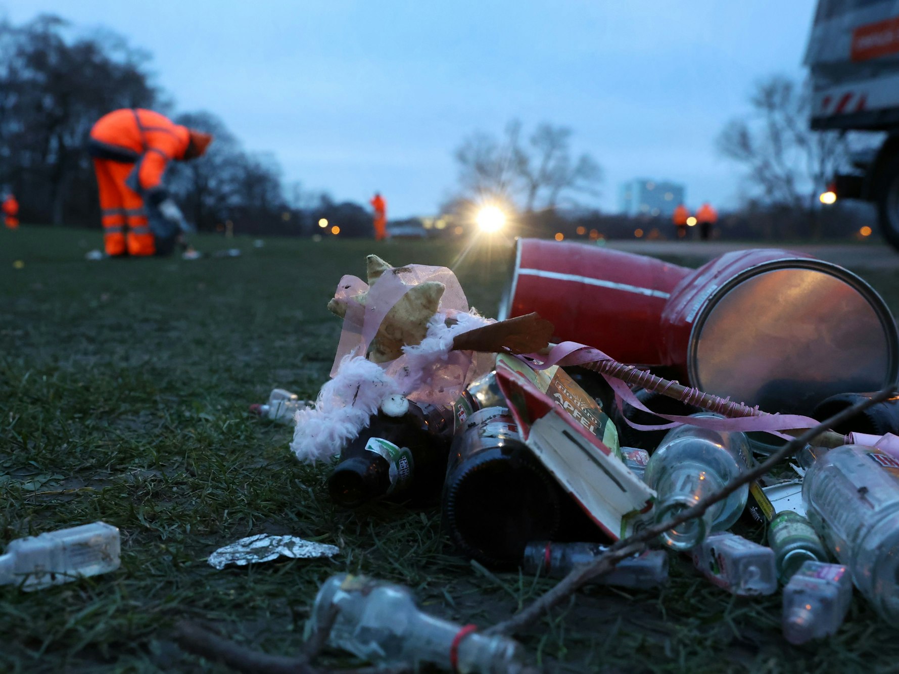 Die AWB sammelt Müll auf einer Grünfläche auf.