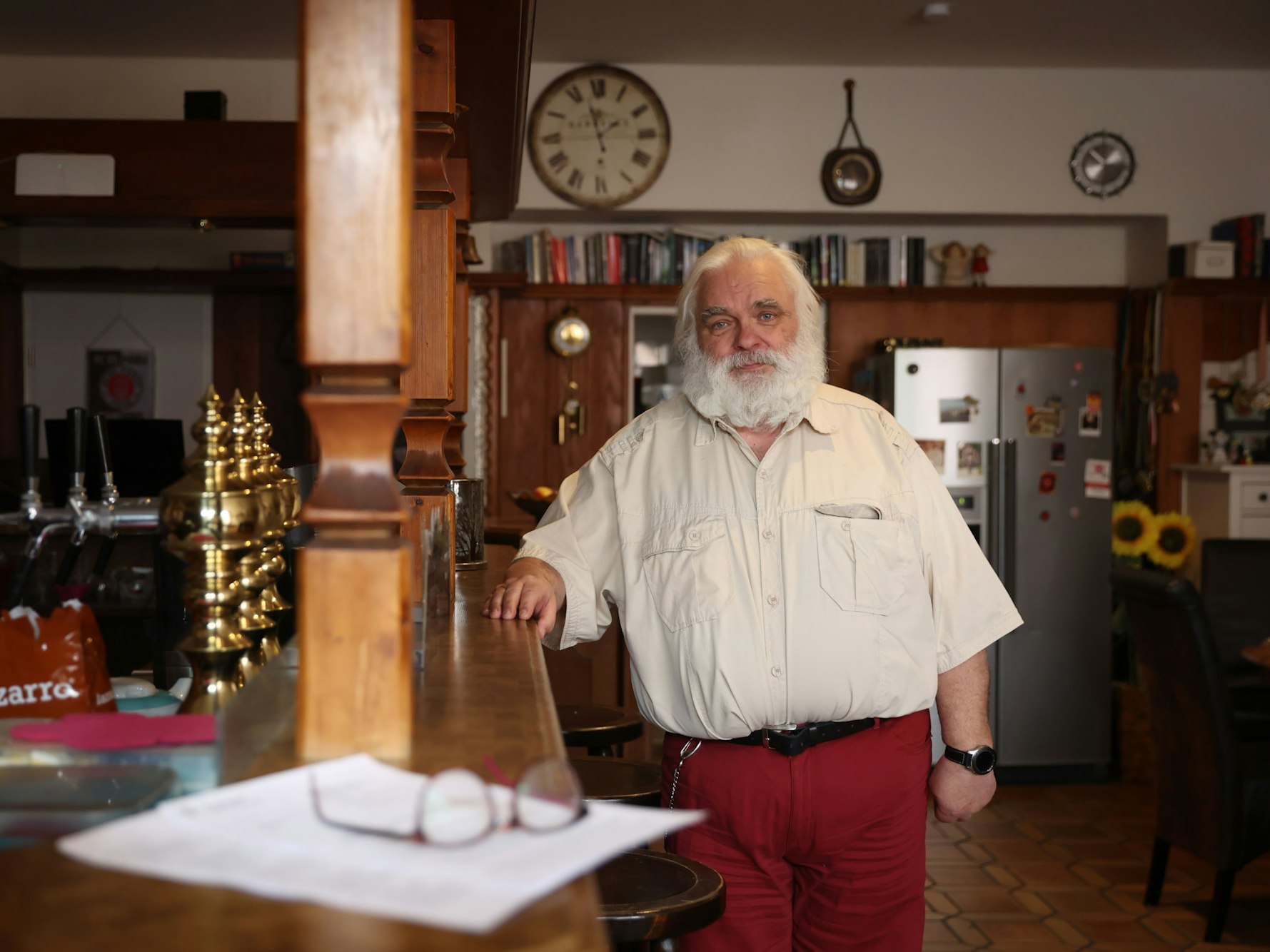 Ein Mann steht in einer Wohnung und lehnt sich an einen Tresen an.