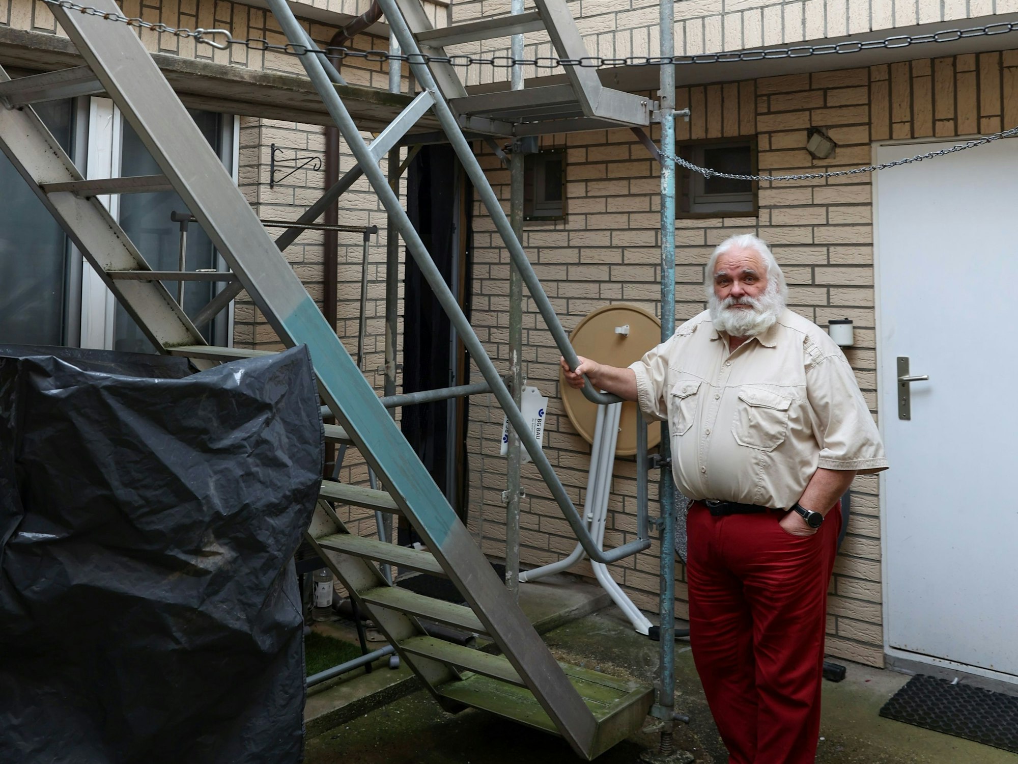 Ein Mann steht neben einer Treppe im Hof.