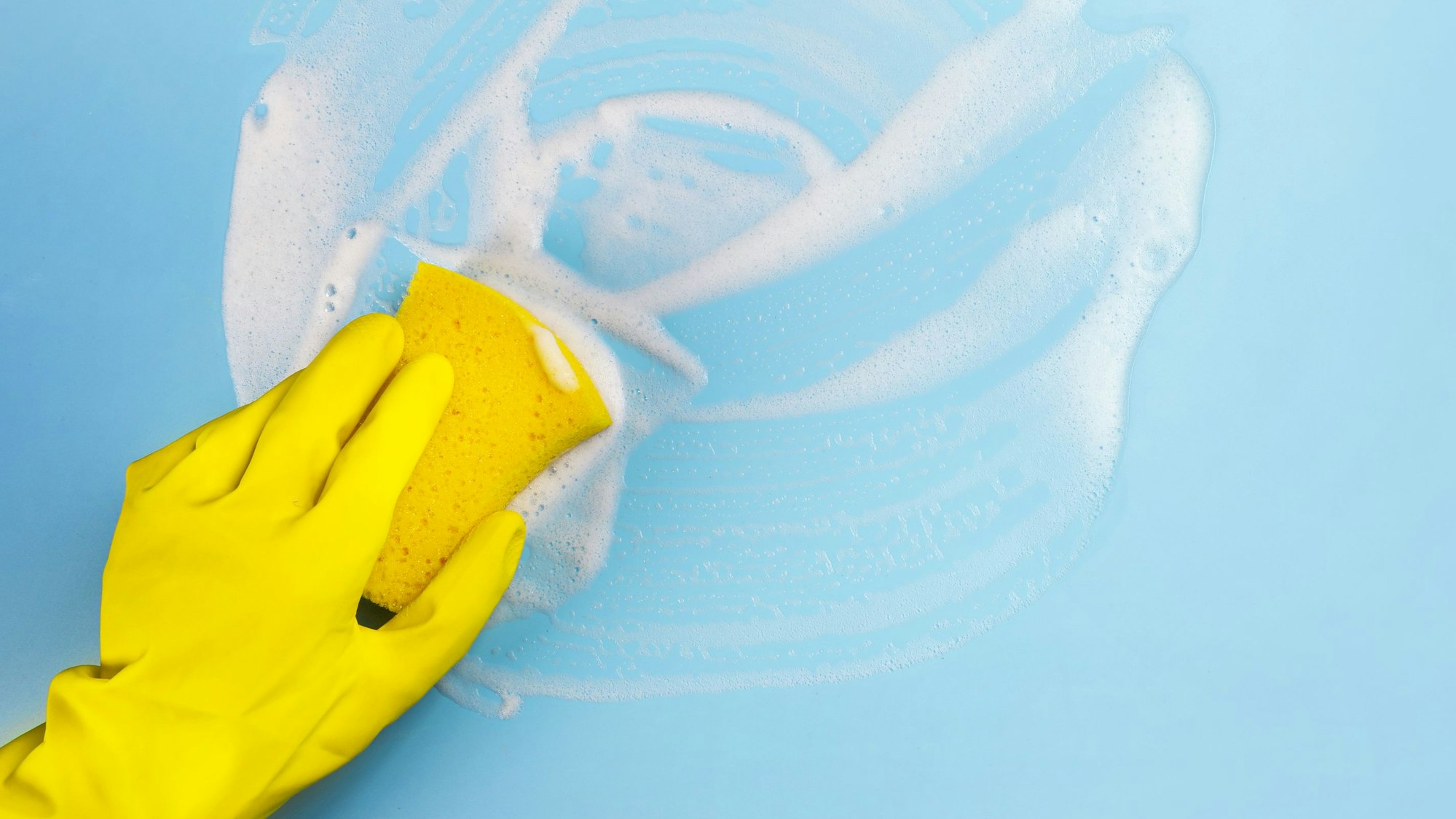 Jemand reinigt mit einem Schwamm eine blaue Unterlage.