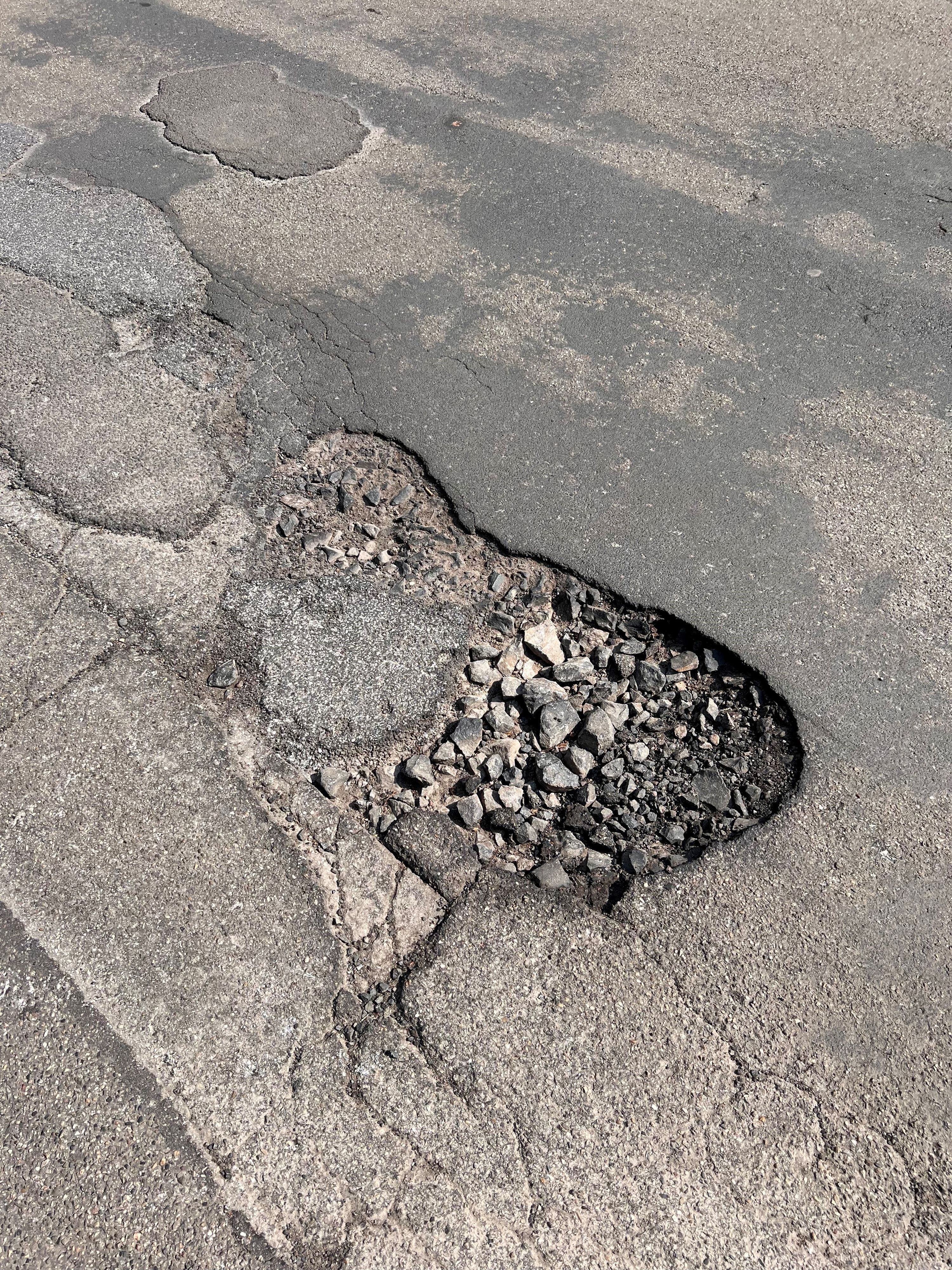 Ein tiefes Schlagloch auf einer Straße in Köln