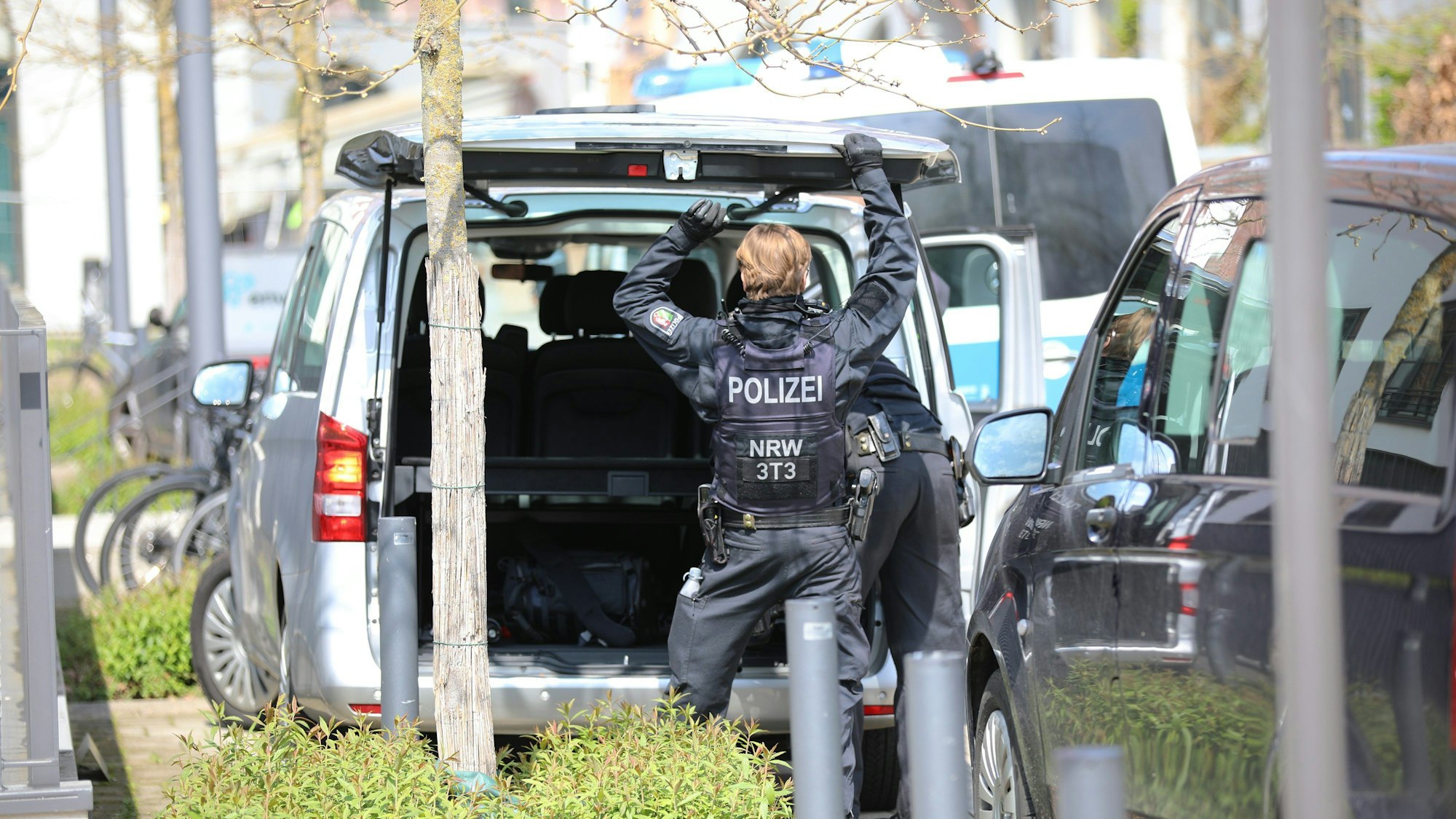 Ein Polizist steht an einem Auto.