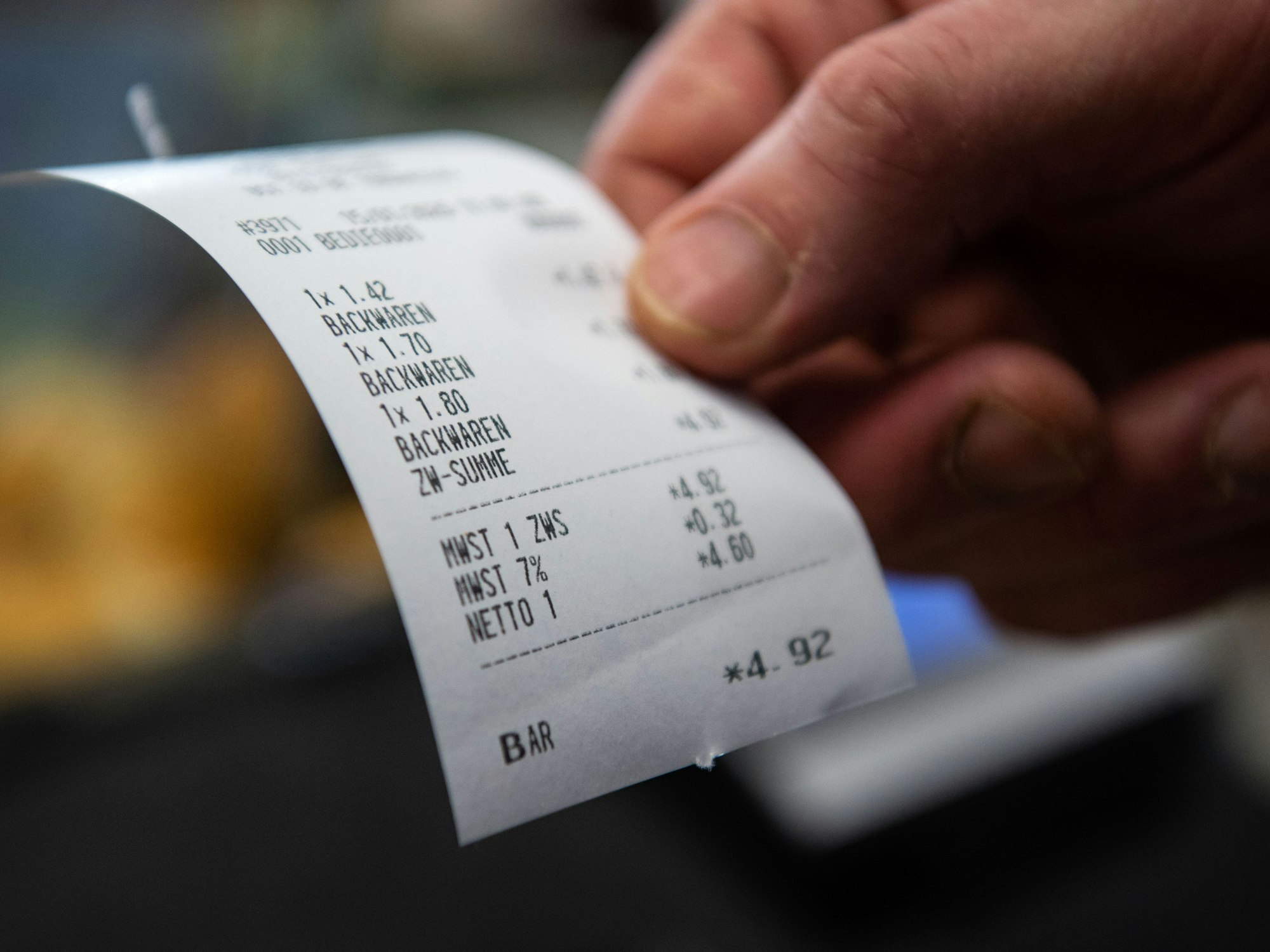 Hier zu sehen, eine Person hält einen Kassenbeleg mit verbuchten Backwaren in der Hand.