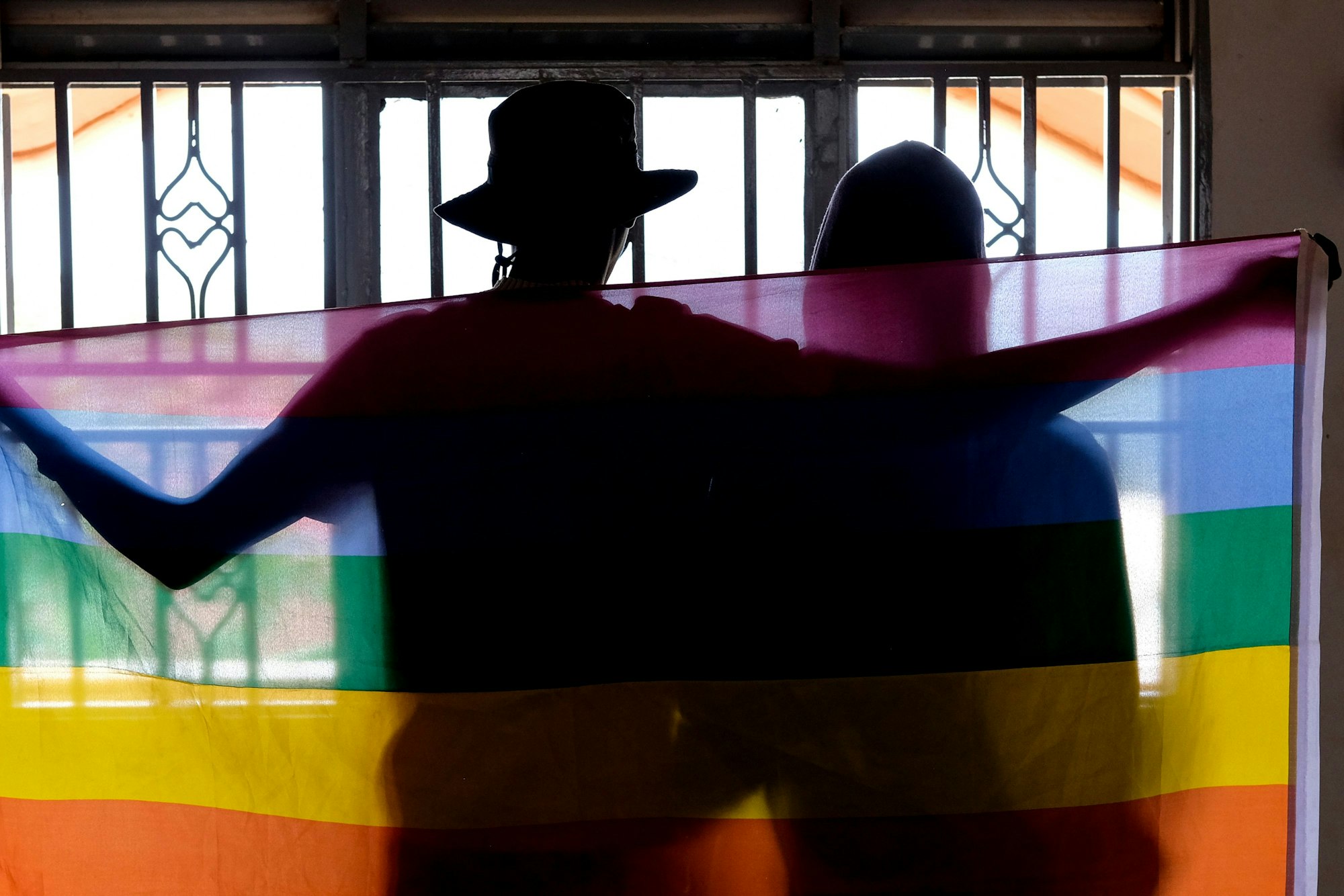 Ein schwules Paar bedeckt sich mit einer Pride Flagge, während sie für ein Foto in Uganda posieren.