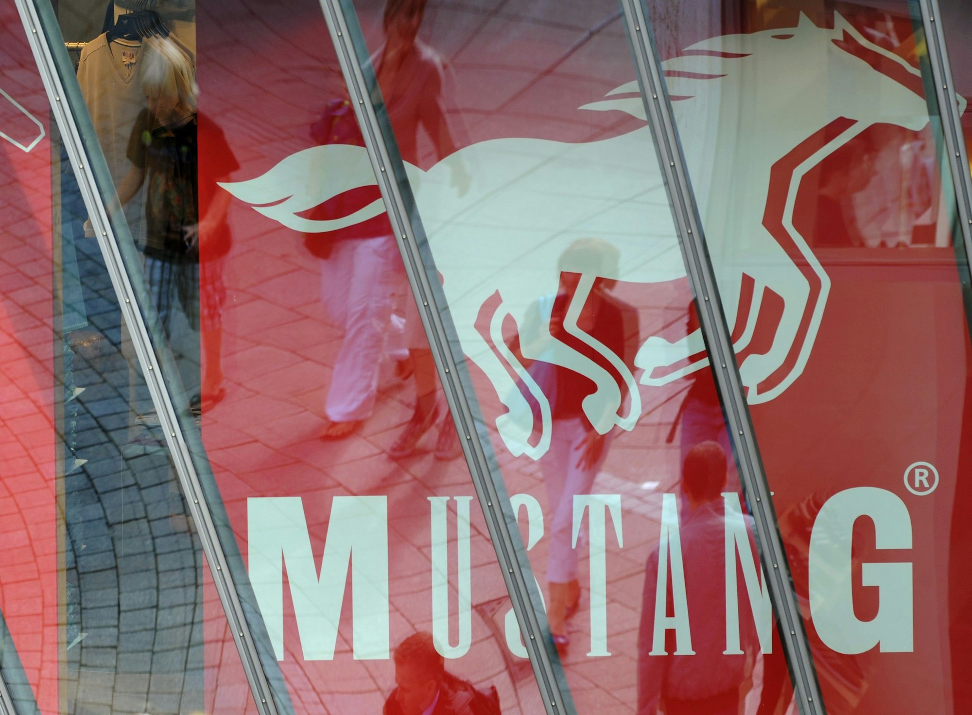 ARCHIV - Passanten auf der Königstraße in der Innenstadt von Stuttgart (Baden-Würtemberg) spiegeln sich in einer Schaufensterscheibe eines Mustang-Stores. Der Jeanshersteller Mustang will seinen Wachstumskurs im Jahr 2014 mit einem Ausbau des Großhandels fortsetzen. Geschäftsführer Axt rechnet 2014 erneut mit einem Umsatzplus von rund 20 Prozent, wie das Unternehmen mit Sitz in Künzelsau am 08.01.2014 mitteilte. Foto: Marijan Murat/dpa (zu lsw: «Jeanshersteller Mustang will mit Großhandelsgeschäft wachsen» vom 08.01.2014) +++ dpa-Bildfunk +++
