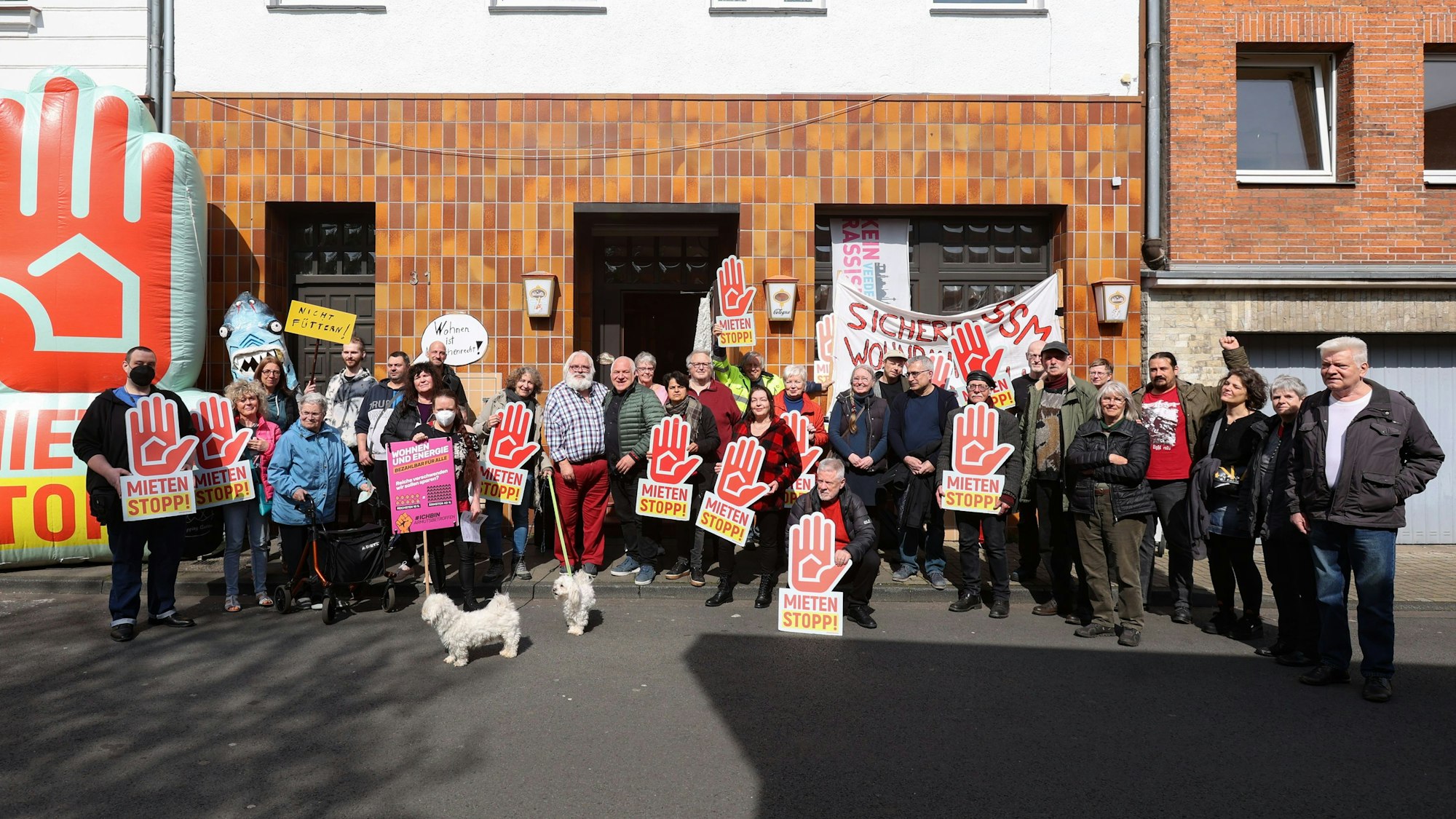Menschen stehen bei einer Demo vor einem Wohnhaus.