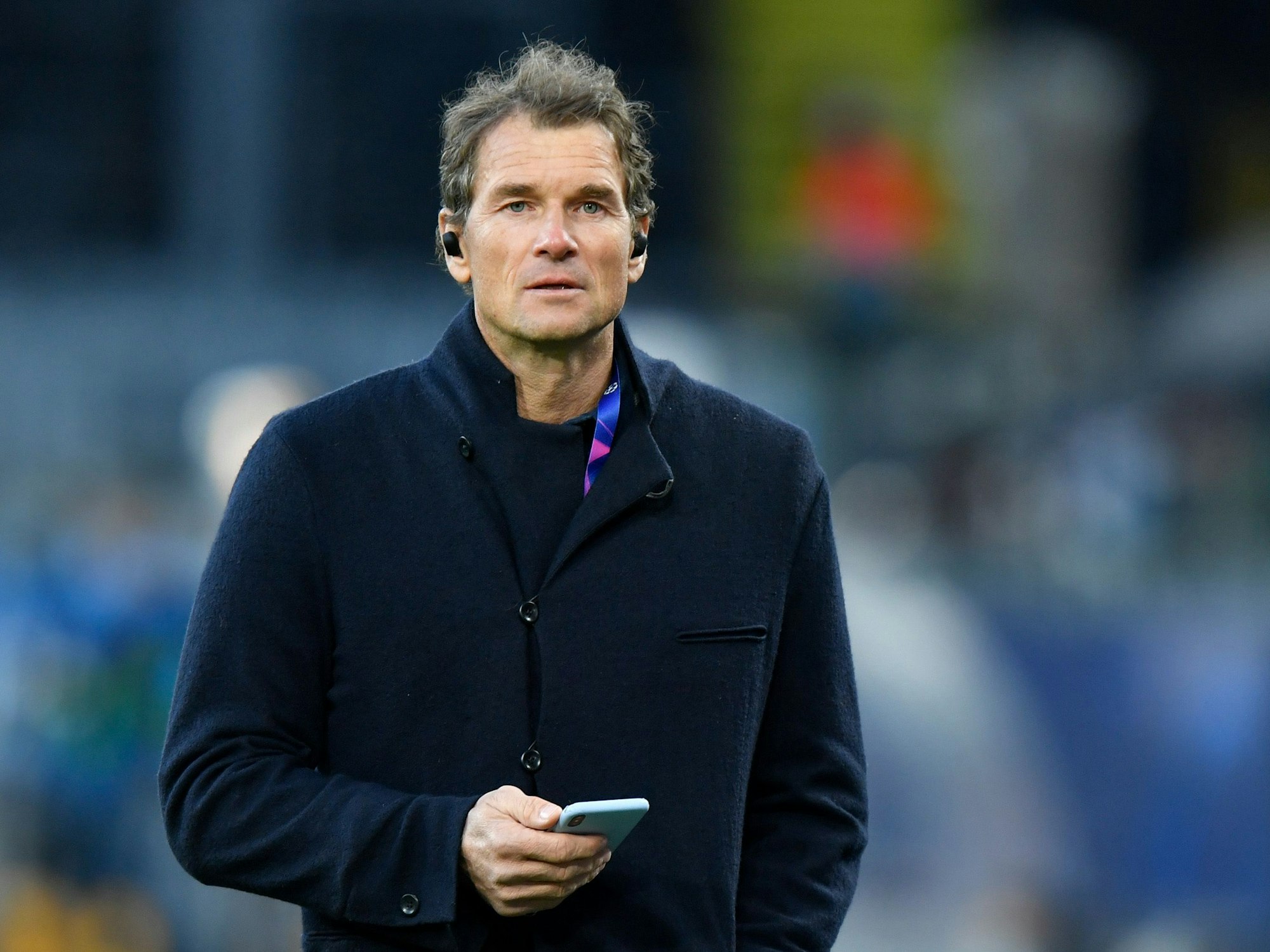 Jens Lehmann vor einem Spiel in Dortmund mit Handy und Kopfhörern.