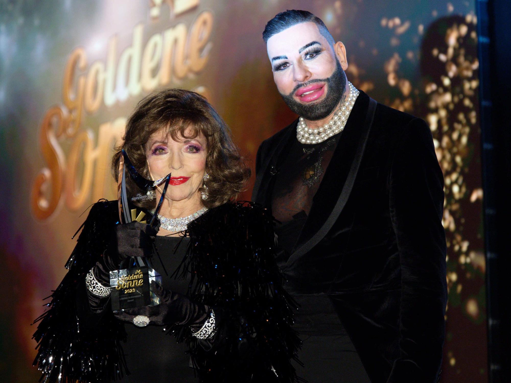 Die Schauspielerin Dame Joan Collins erhält bei der Verleihung der "Goldenen Sonne" 2023 des Reisesenders sonnenklar.TV den "Lifetime Achievement Award" von Laudator Harald Glööckler.