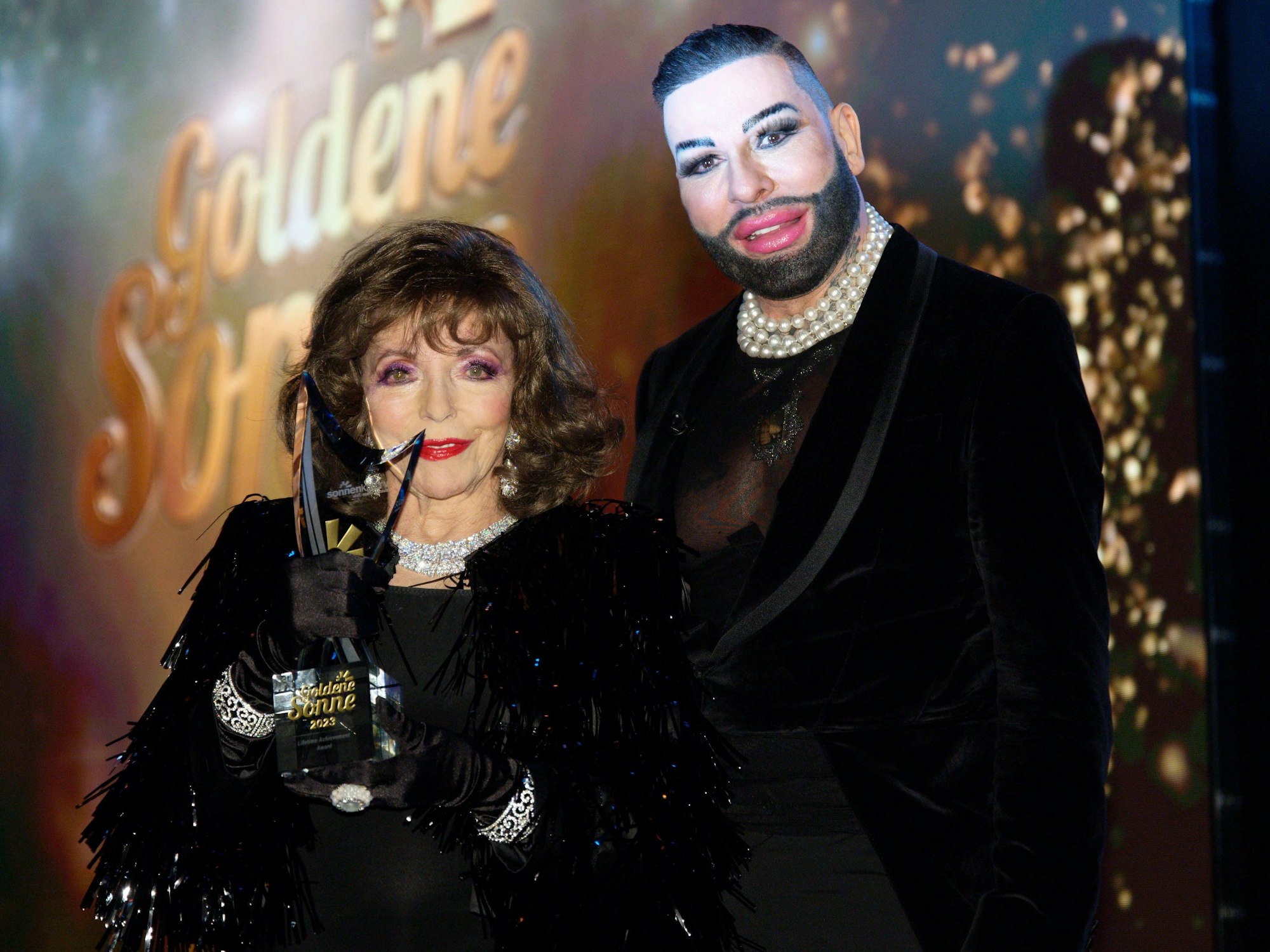 Die Schauspielerin Dame Joan Collins erhält bei der Verleihung der "Goldenen Sonne" 2023 des Reisesenders sonnenklar.TV den "Lifetime Achievement Award" von Laudator Harald Glööckler.