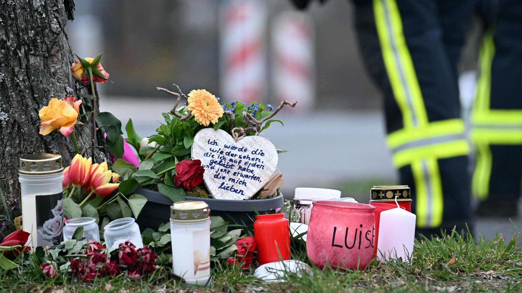 Kerzen und Blumen liegen an einem Baum an der Gesamtschule.