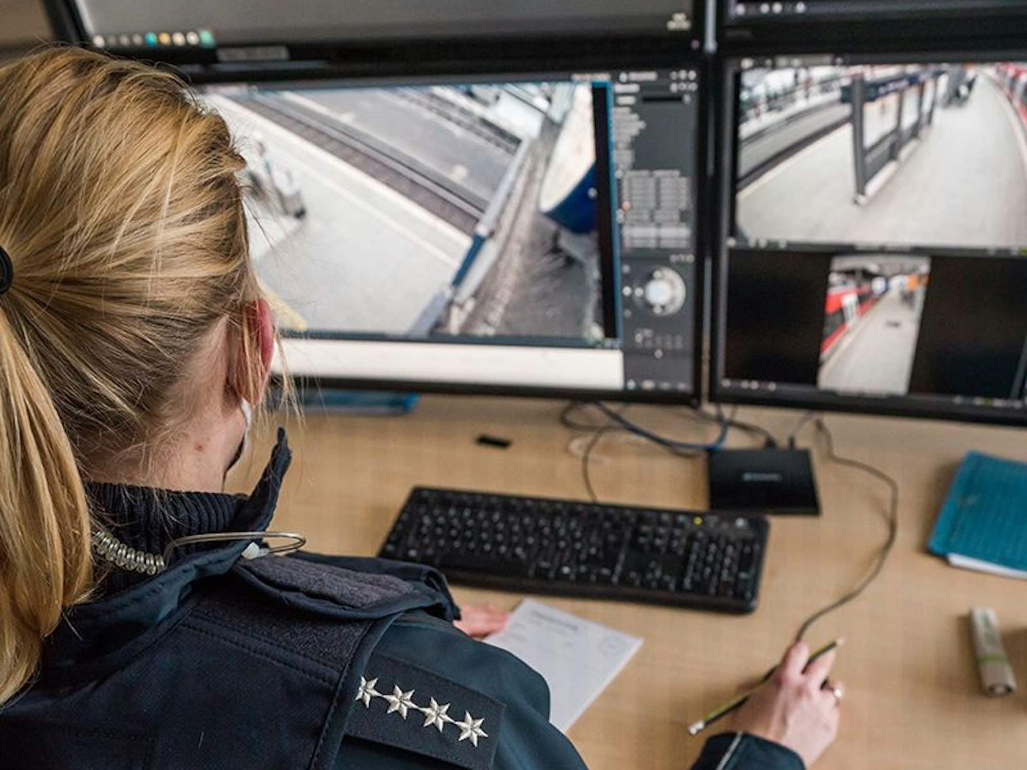 Eine Bundespolizistin sitzt vor Bildschirmen, über welche die Bilder der Videoüberwachung flimmern.