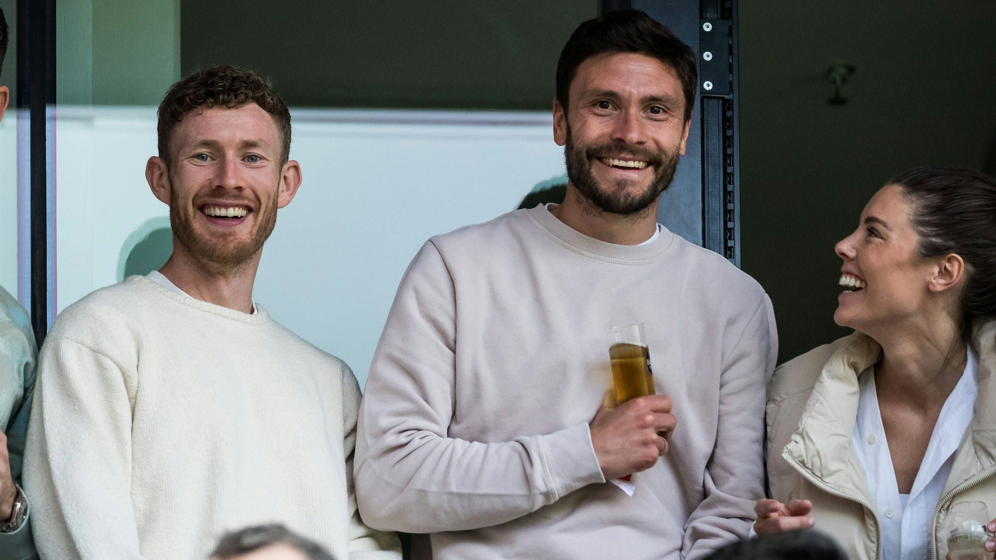 Jonas Hector lacht beim Spiel der FC-Frauen im Rhein-Energie-Stadion mit seiner Frau Anika und Florian Kainz.