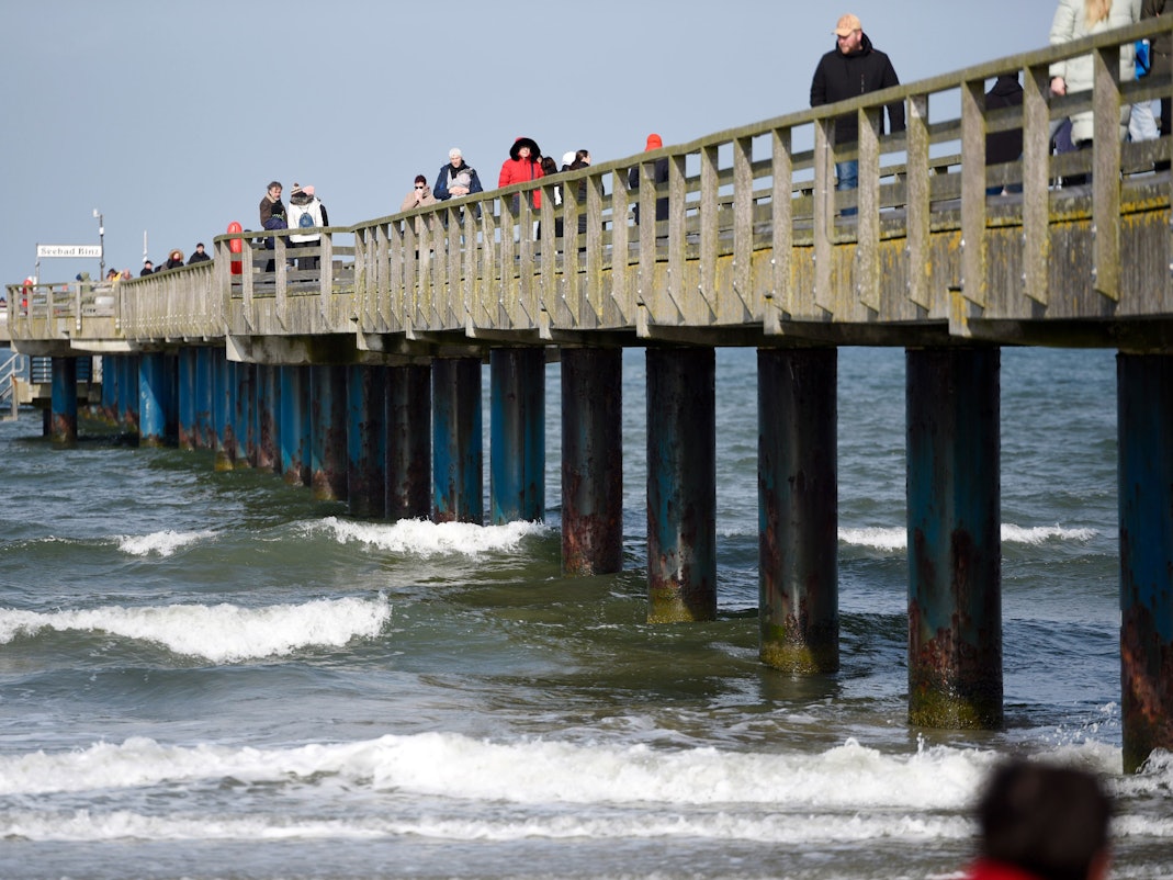 Spaziergänger laufen auf der Seebrücke vom Ostseebad Binz auf der Insel Rügen.