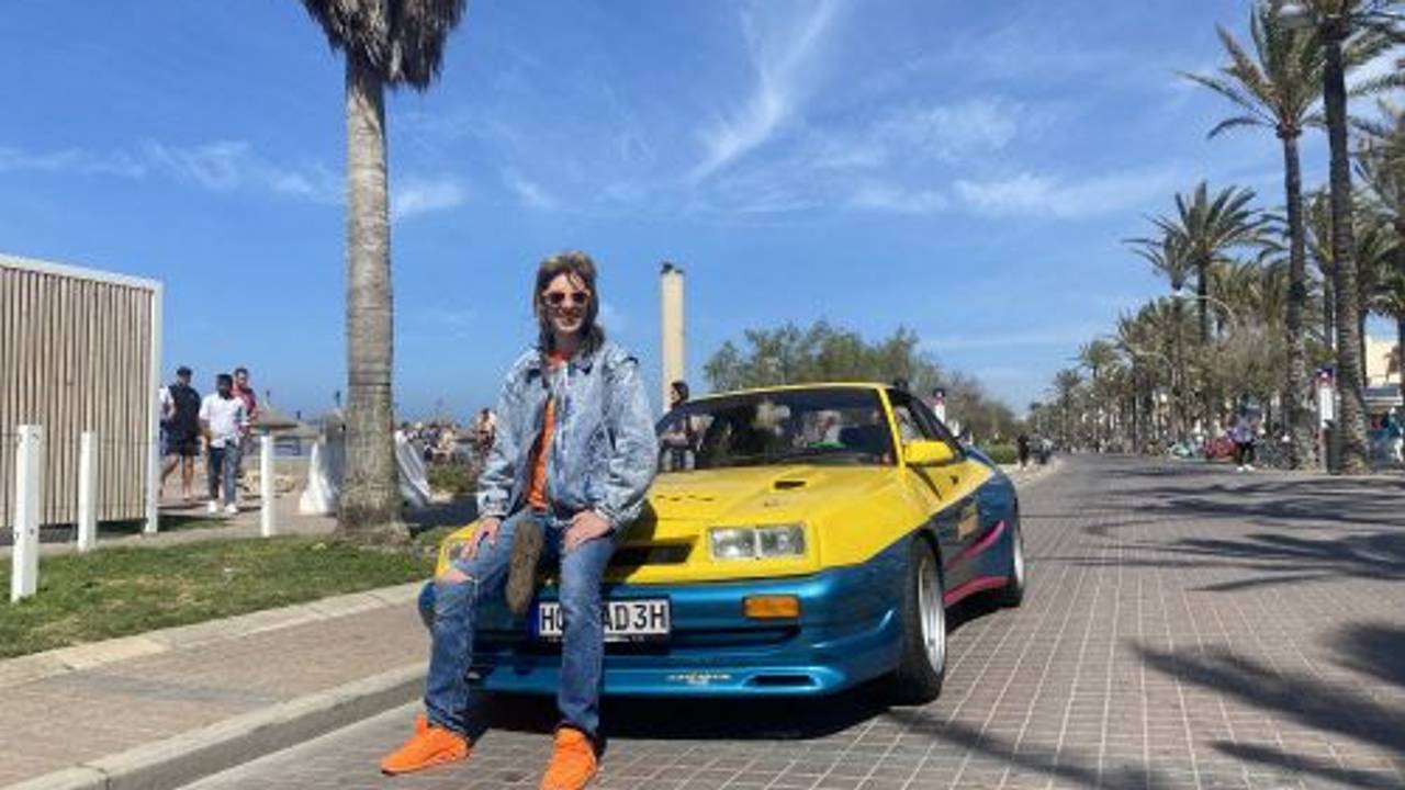 Manni Manta sitzt auf dem Opel Manta am Ballermann auf Mallorca.