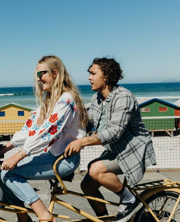 Drei Freunde lachen und fahren einen Tandem Fahrrad.