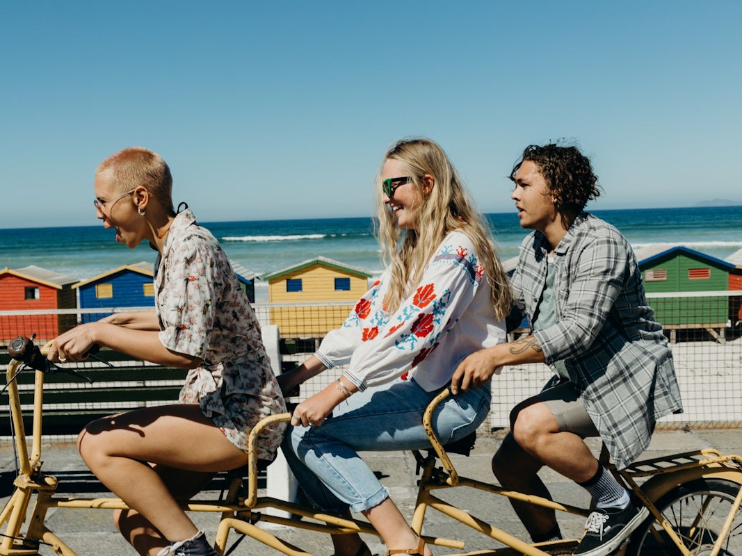 Drei Freunde lachen und fahren einen Tandem Fahrrad.
