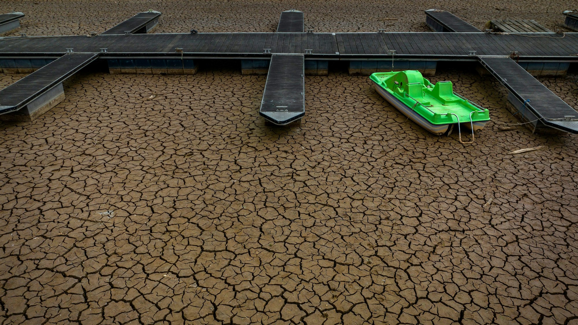 Das Foto vom 18. April 2023 zeigt den ausgetrockneten spanischen Stausee „Vilanova de Sau“. Der Boden unter dem Anlegesteg ist trocken und rissig.