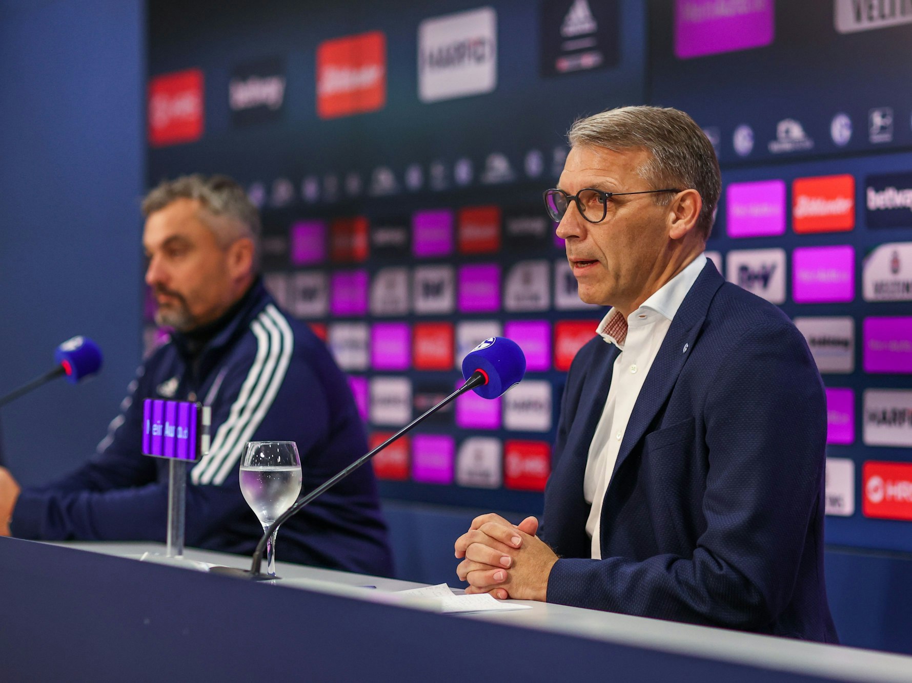 Schalkes Cheftrainer Thomas Reis gemeinsam mit Sportvorstand Peter Knäbel auf einer Pressekonferenz.