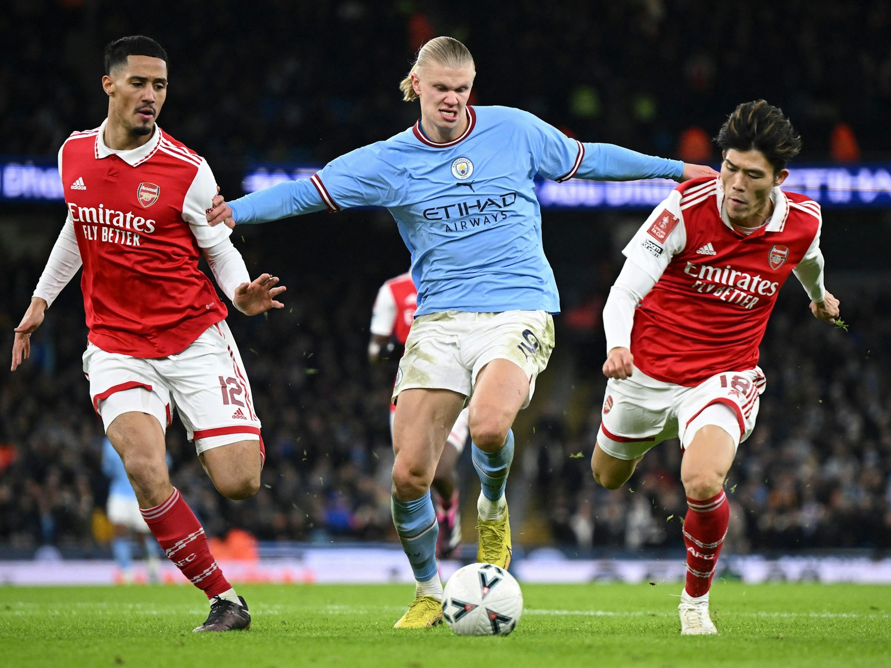 Manchester City Stürmer Erling Haaland (m.) im Zweikampf mit Takehiro Tomiyasu (r.) und William Saliba (l.) beim letzten Aufeinadertreffen beider Teams am 27. Januar 2023