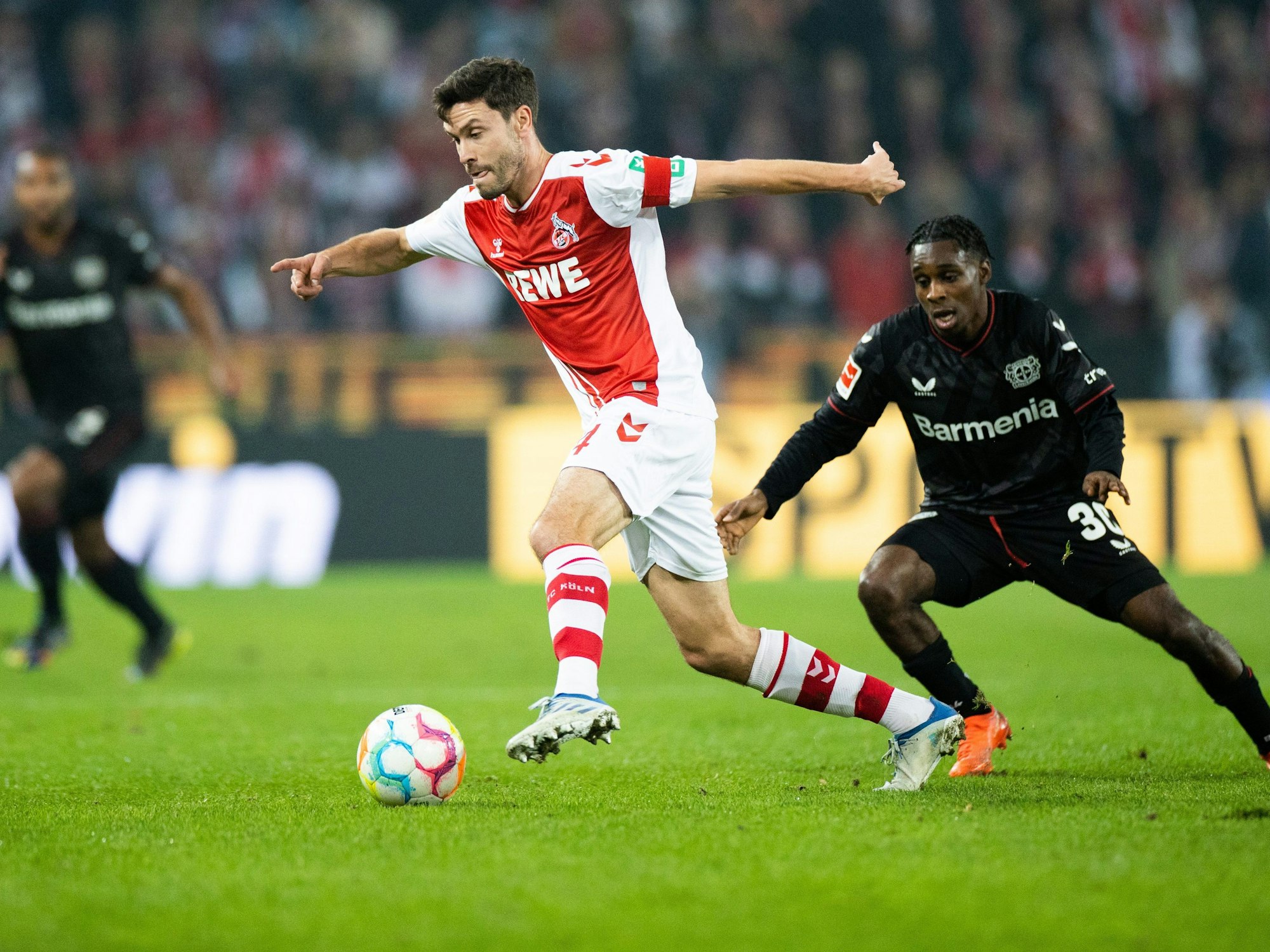 Kölns Jonas Hector und Leverkusens Jeremie Frimpong versuchen an den Ball zu kommen.