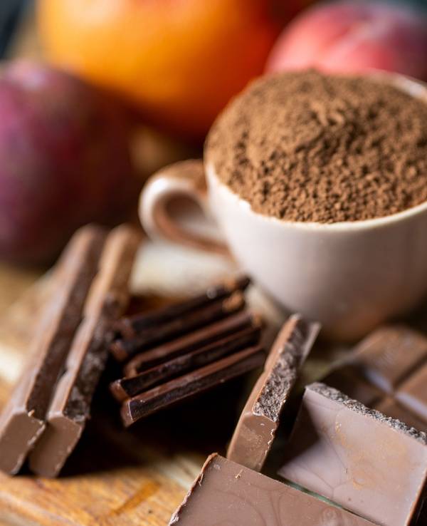 Vollmilchschokolade liegt neben einer mit Kakaopulver gefüllten Tasse auf einem Holzbrett in der Küche, hier im September 2021 in Berlin.